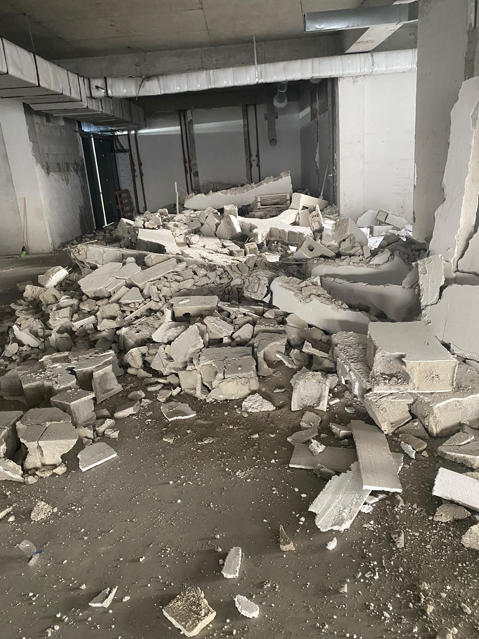 Pereți din blocuri demolați într-un spațiu la subsol, cu moloz pe podea