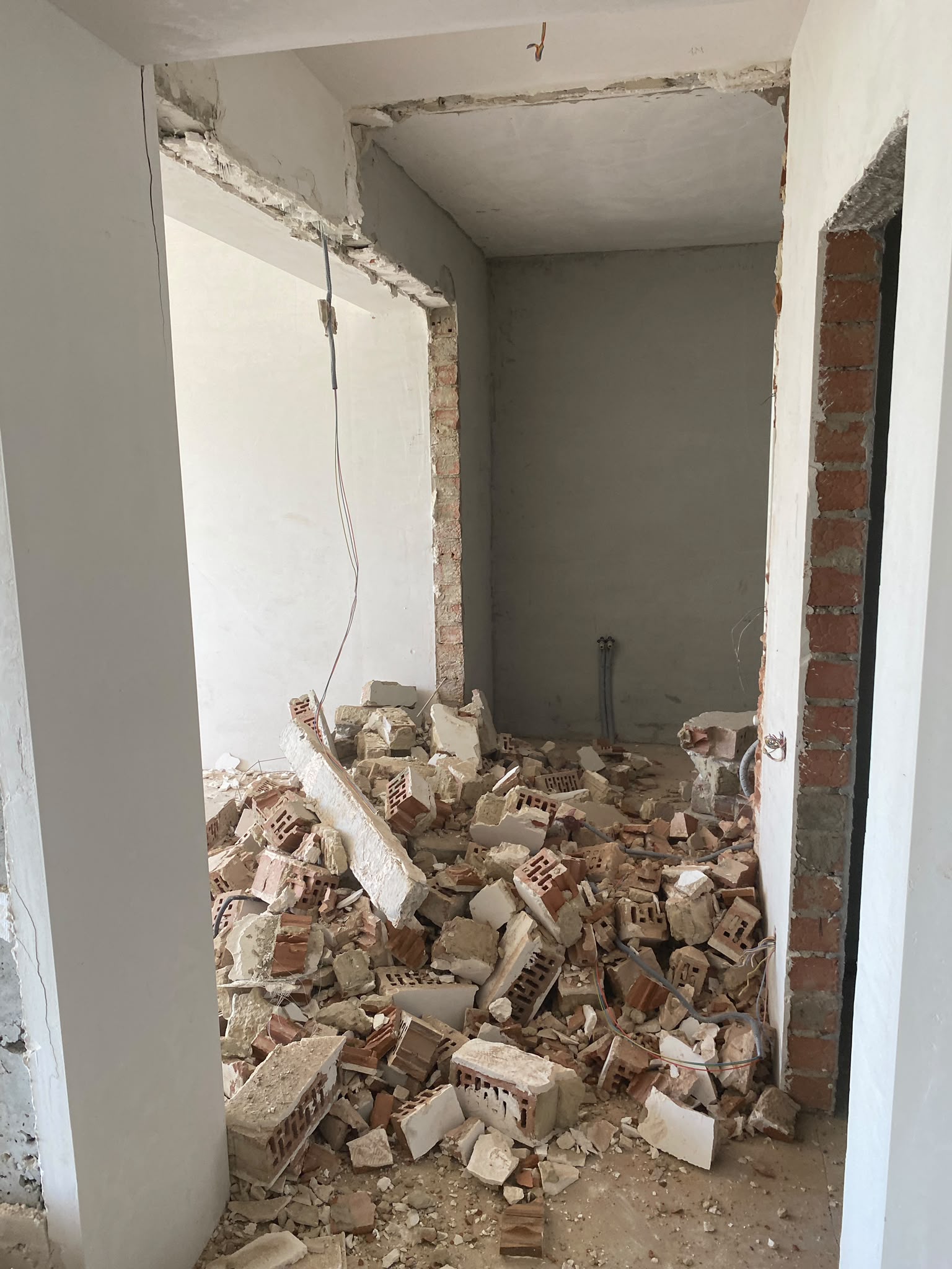 Deschidere nouă în perete și grămadă de cărămidă și gips demolat într-un apartament